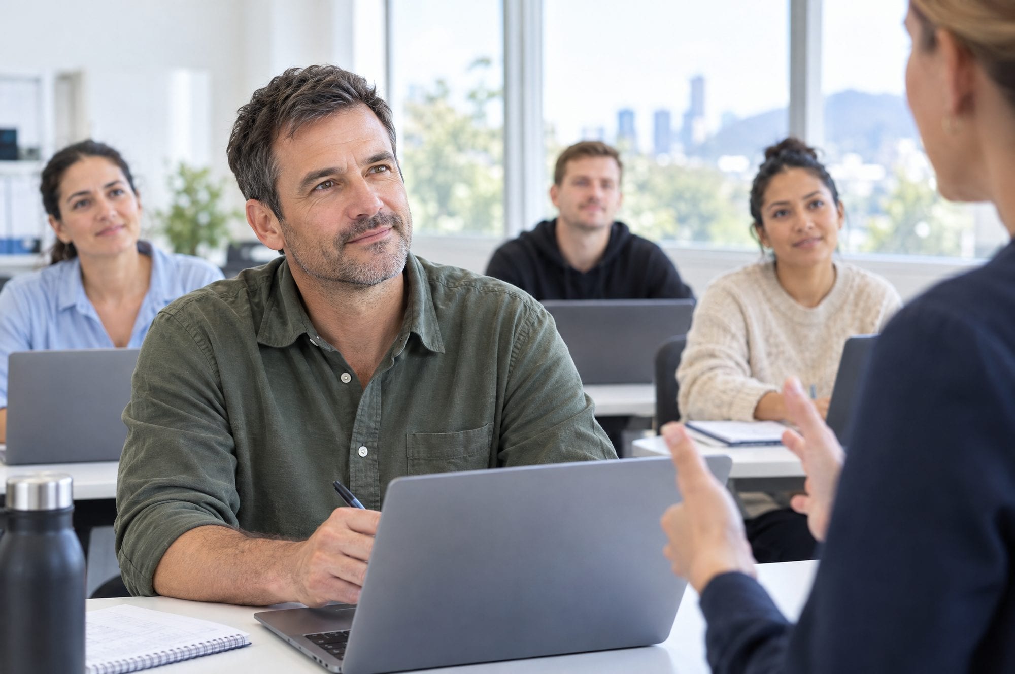 An adult learner listening to a trainer in a bright classroom